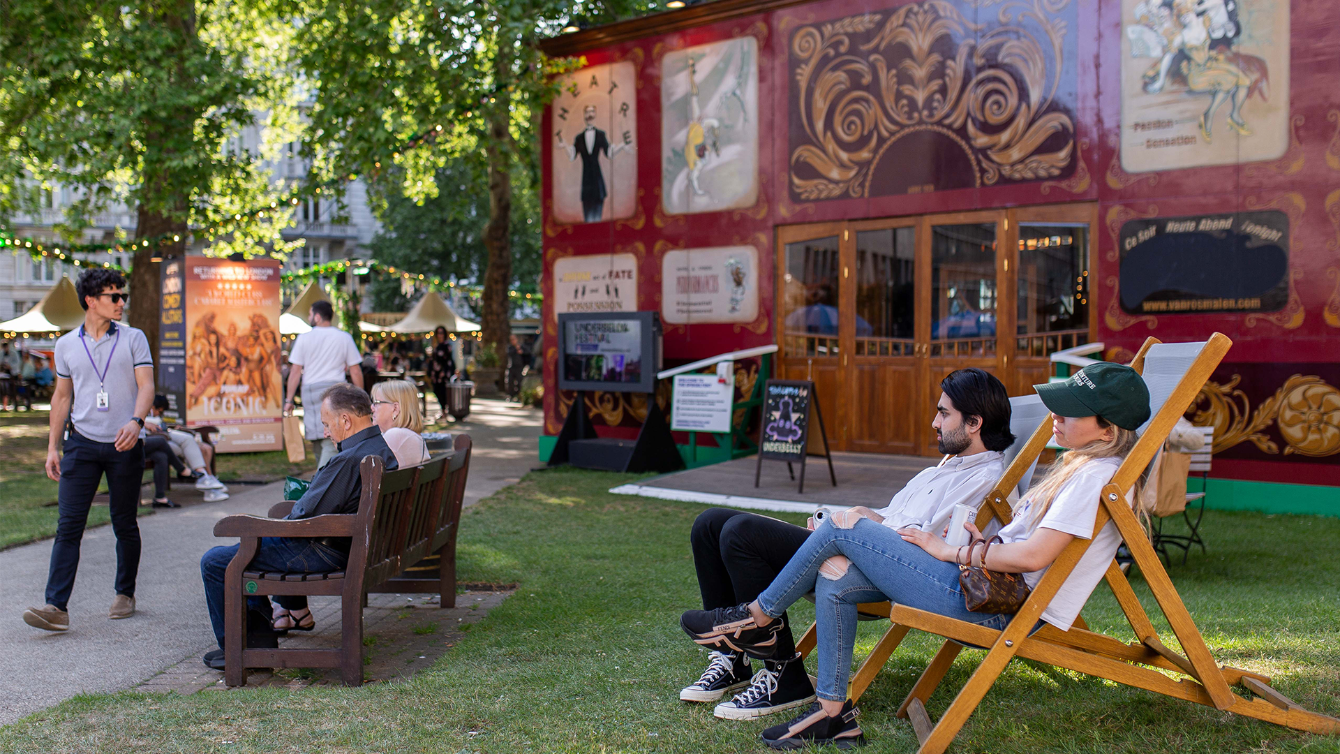 a couple sit on deck chairs outside the Spiegeltent on a summers day