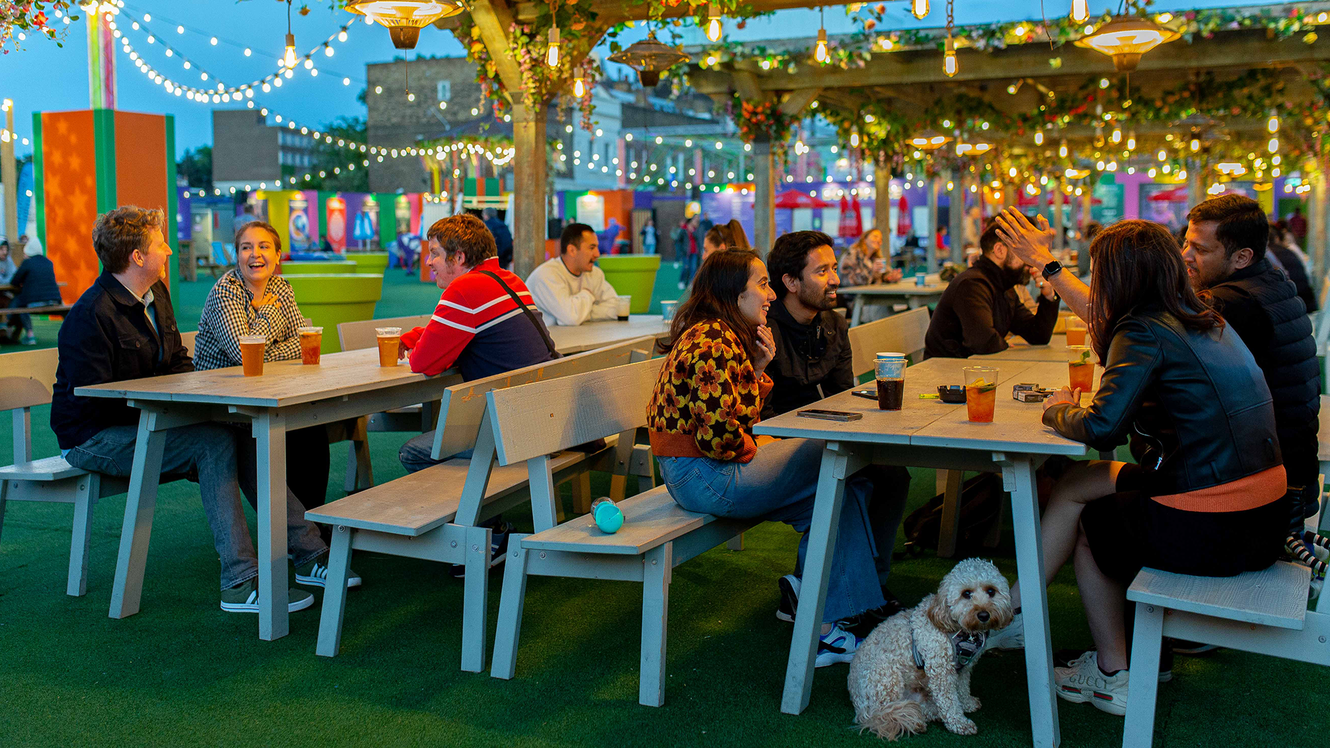 groups of friends sat outside drinking under fairy lights